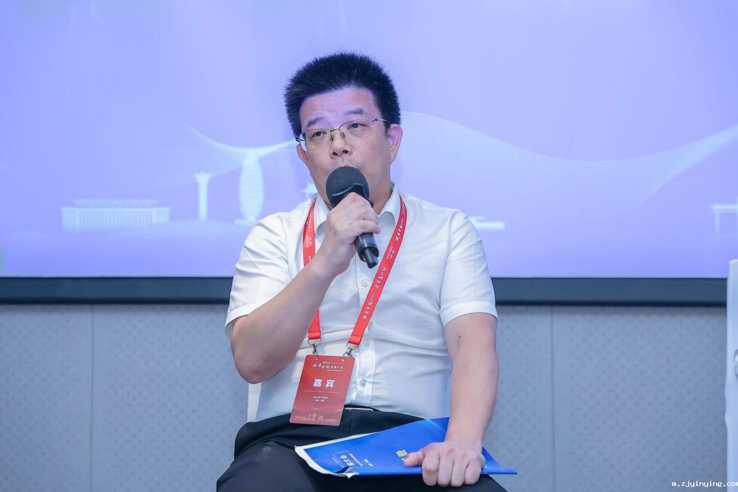 A person holding a microphoneDescription automatically generated